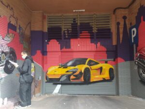 Graffiti de coche deportivo en persiana de parking, destacando la velocidad y la modernidad.