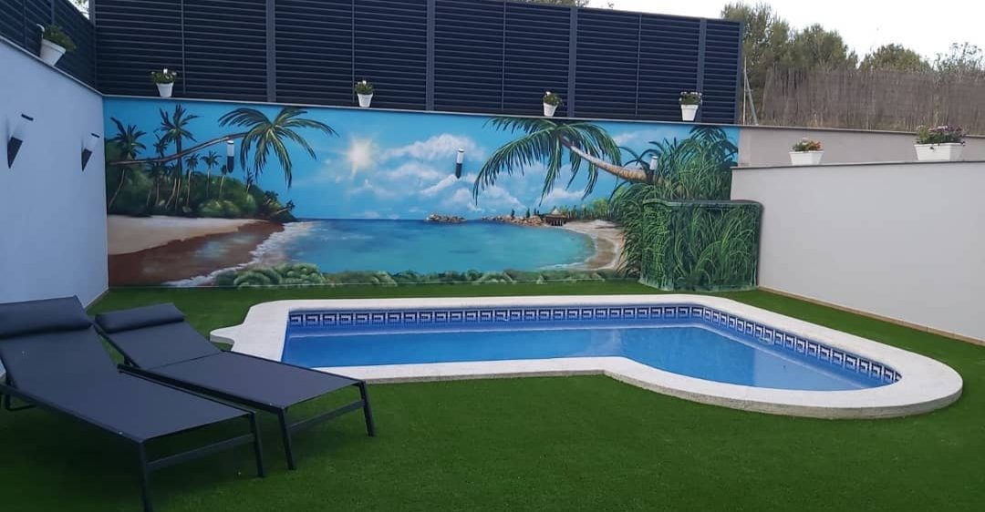 Mural con un paisaje de playa tropical, decorando un patio con piscina para un ambiente relajante.